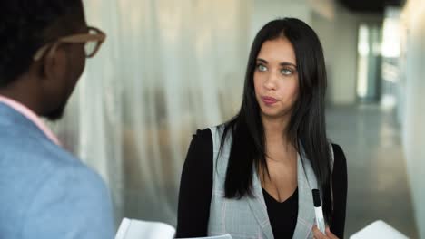 concentrated young brunette talking to coworkers