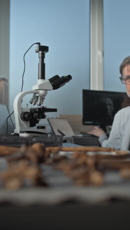 scientist examining fossils under microscope