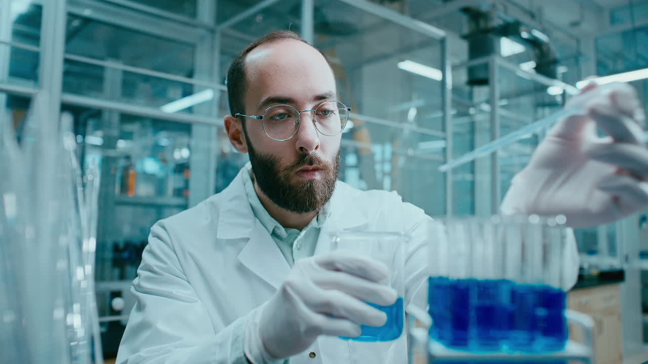 Científico de laboratorio transfiriendo muestras químicas azules con pipeta a tubos de ensayo