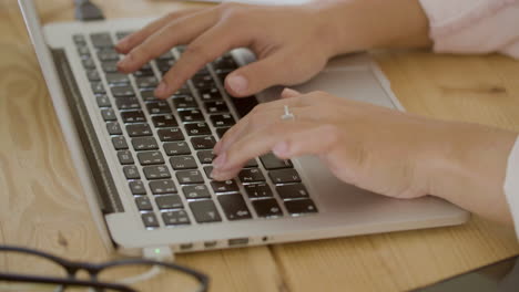 primer plano de las manos de una mujer joven escribiendo en el teclado de un portátil