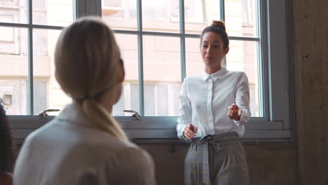 Female-boss-addresses-female-colleagues-at-meeting,-close-up