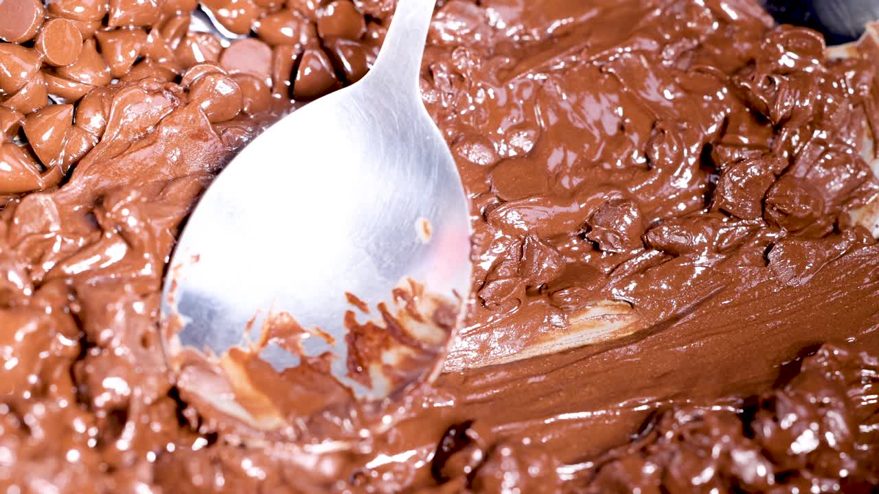 Spoon stirring melting chocolate chips in pan