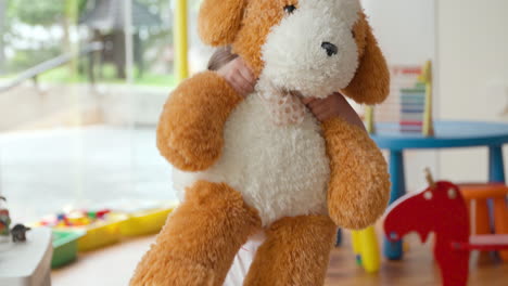 A-girl-shows-her-large-stuffed-animal-dog-playfully-in-slow-motion-in-a-brightly-lit-playroom