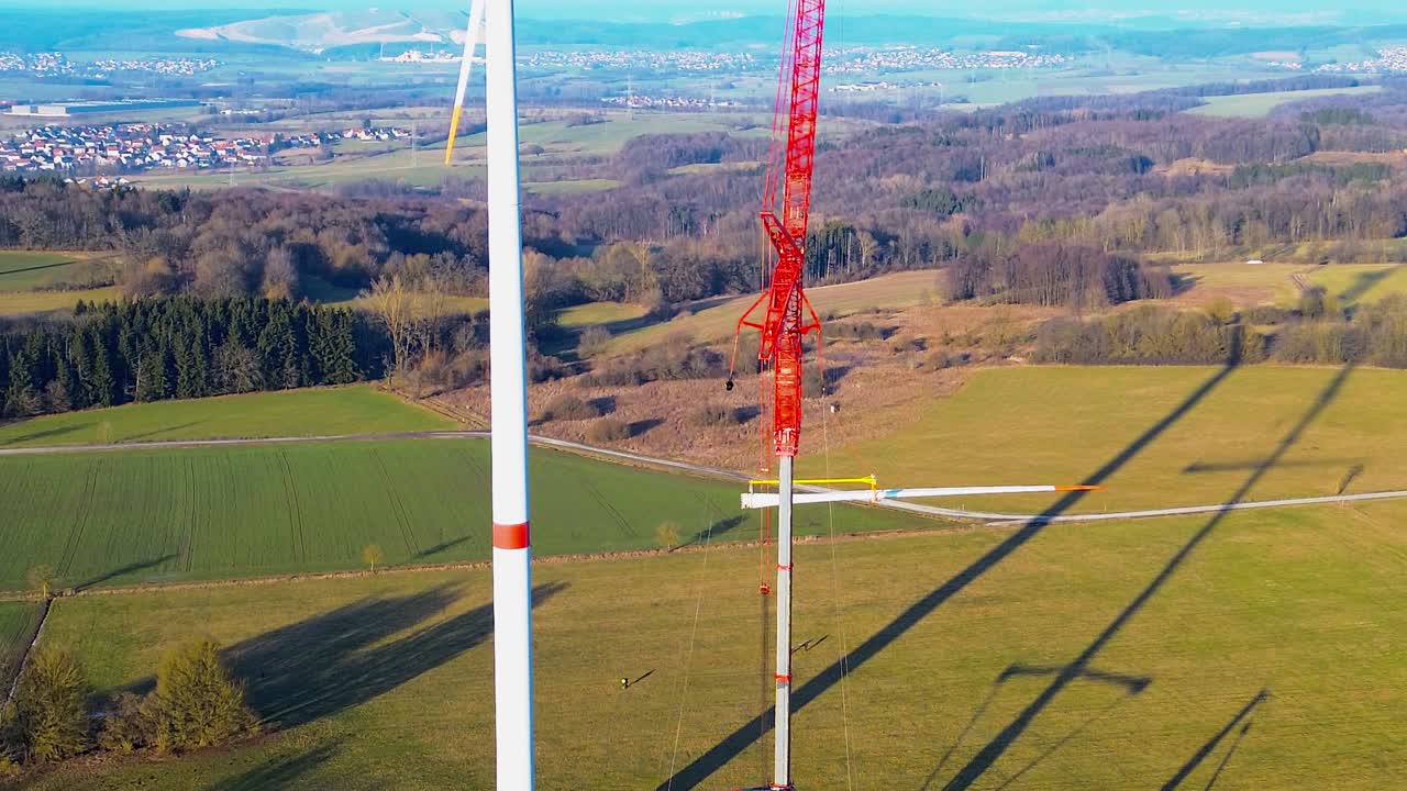 Aerial close up of wind turbine blade installation with crane in rural Germany