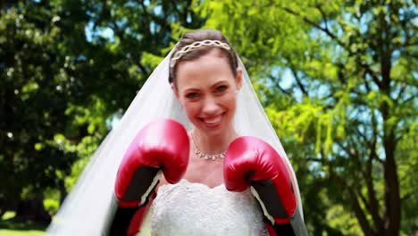 pretty bride smiling at camera and wearing boxing gloves