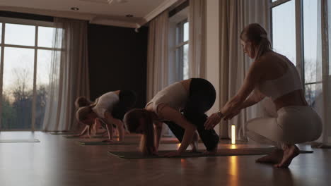 grupo de mujeres jóvenes practicando yoga con la ayuda de un instructor. están haciendo asanas de giro lateral sentadas. en una habitación brillante.