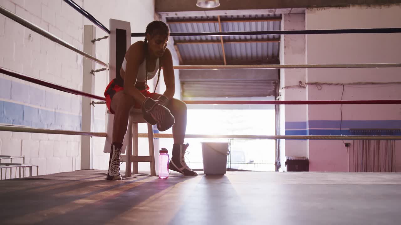 Mixed race woman resting in boxing gym