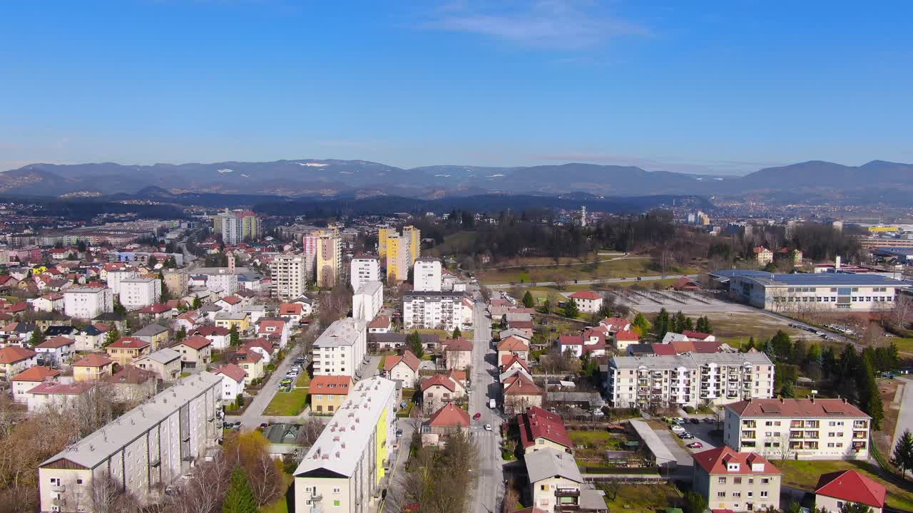 Aerial: Dolly in flight over Celje City in Slovenia with urban landscape with lots of block of flats and houses during a sunny day