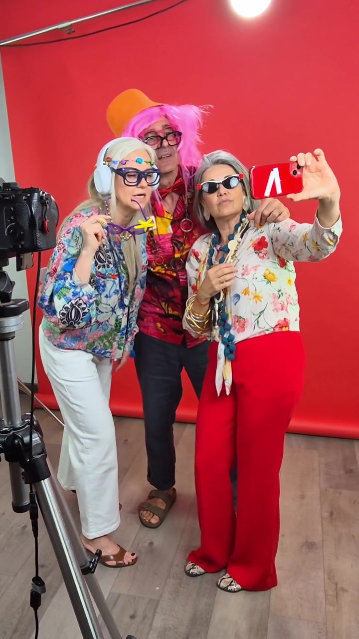 Amici anziani in costumi divertenti che si scattano selfie in uno studio