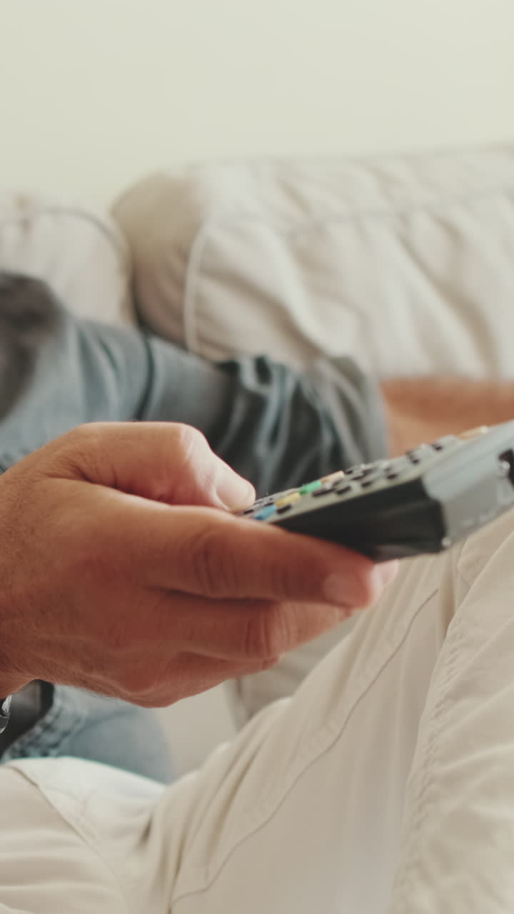 Persona che usa un telecomando su un divano