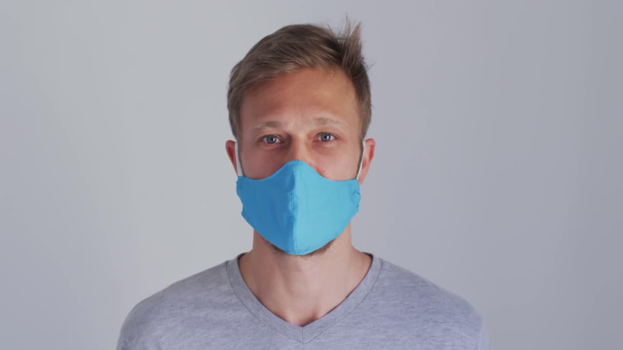 Portrait of a caucasian man wearing a blue face mask and grey t shirt