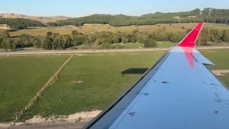 el ala derecha del avión y la sombra se acercan a la pista en una tarde soleada