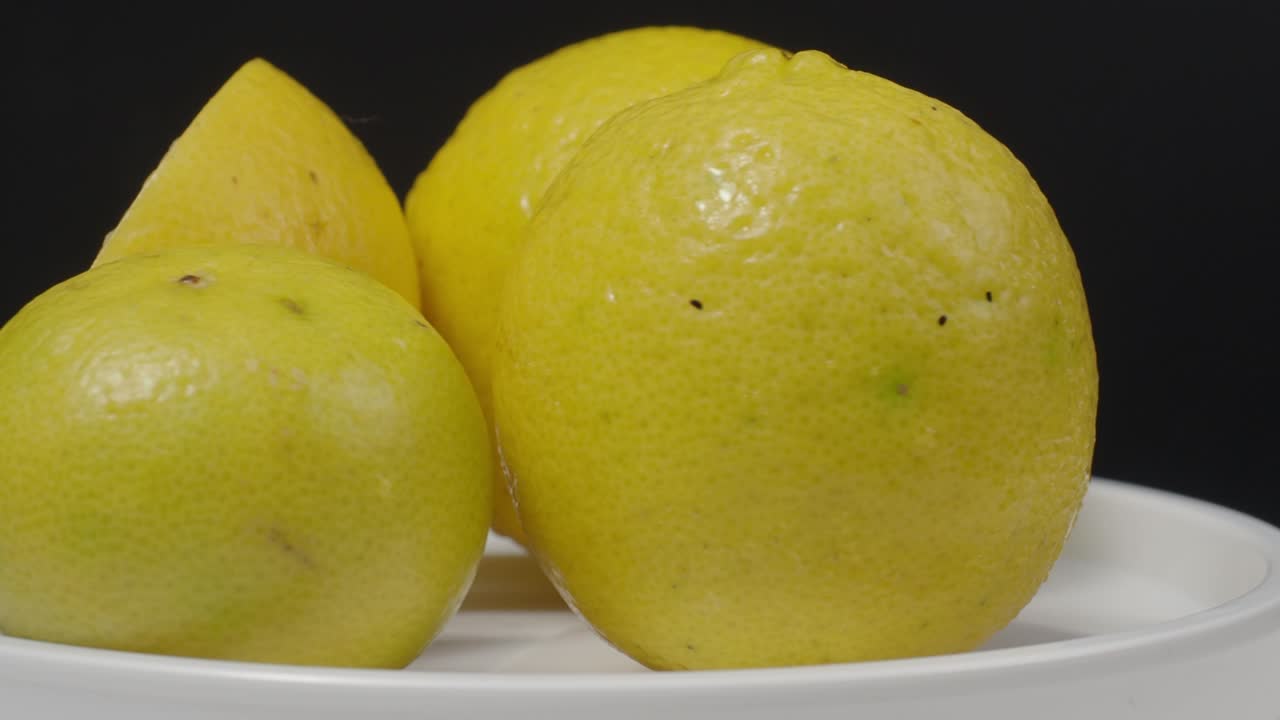 limón delicioso moviéndose en la mesa giratoria. limones sabrosos aislados en el fondo negro. limones amarillos enteros y medio están aislados en fondo oscuro. cerca. representan agrio y refrescante menú de bebidas.