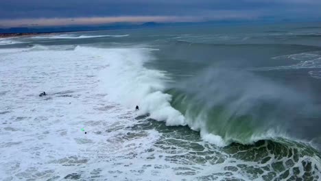 surfer gets towed into a large barreling wave in hossegor, france early morning