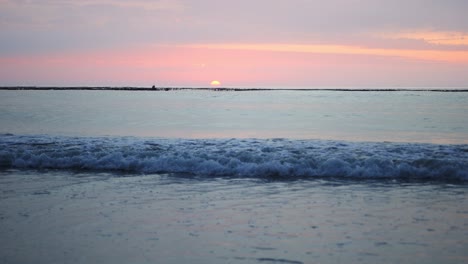 El-Sol-Alcanza-Su-Punto-Máximo-En-El-Horizonte-Mientras-Pequeñas-Olas-Llegan-A-La-Playa-En-Cámara-Lenta