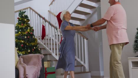 Glückliches-Kaukasisches-älteres-Paar,-Das-Weihnachtsmützen-Trägt-Und-Zur-Weihnachtszeit-Tanzt