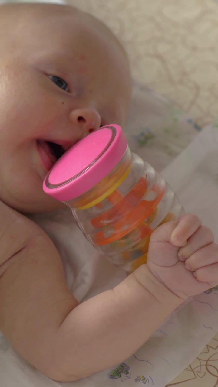 Neonata di due mesi sdraiata nella culla con un sonaglio