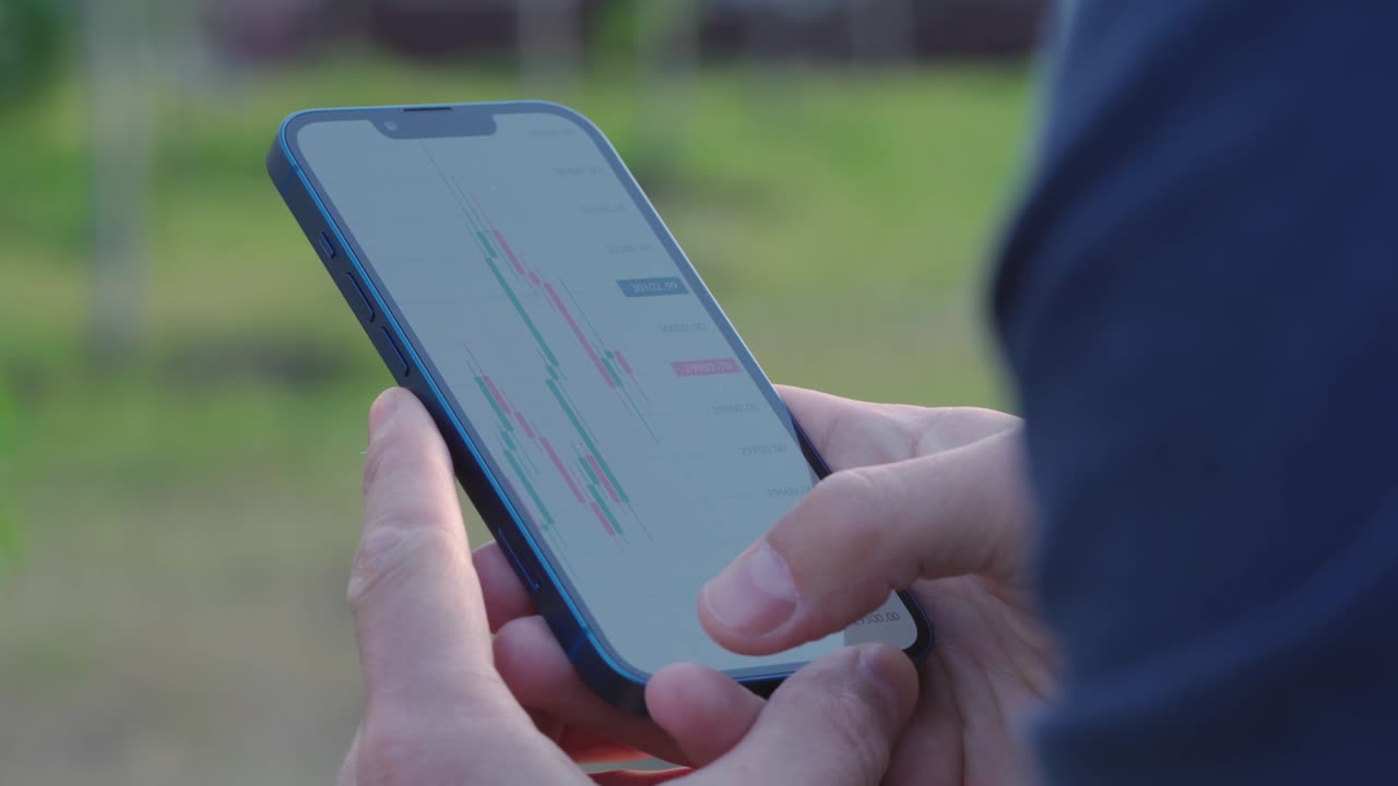 hombre de 4k mira el gráfico de velas de comercio de criptomonedas en la pantalla de su teléfono inteligente