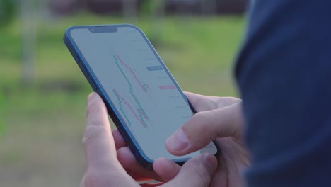 4k man looks at candlestick chart of cryptocurrency trading on smartphone screen