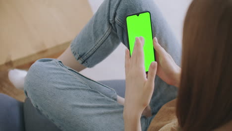 Young-Girl-Is-Holding-Smartphone-With-Green-Screen-At-Evening-Time.-Smartphone-in-hand-static-footage-with-little-hand-moves.-indicators-on-screen-to-track-movement