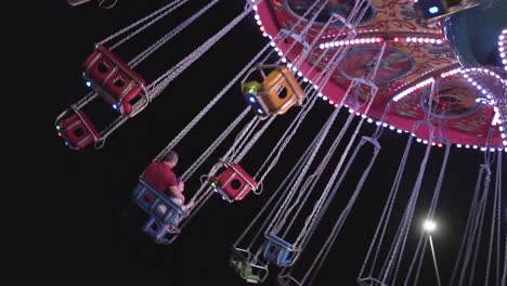 colorful carousel swing seats at night in a park in slow motion