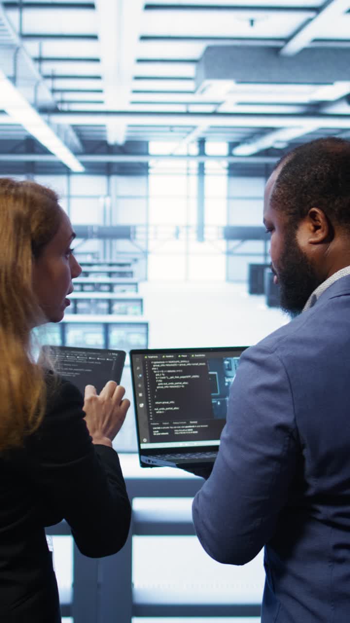 IT Professionals Discussing Data on Laptops in Server Room