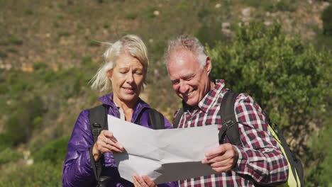 happy senior couple looking at map in moutains