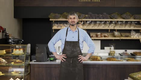 Freundlicher-Männlicher-Bäcker-Wischt-Sich-Die-Hände-An-Einer-Mehlschürze-Ab-Und-Legt-Die-Hände-Auf-Die-Hüften