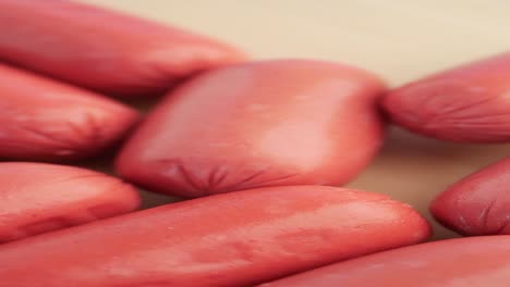 raw pink sausages on wooden surface