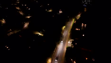 Driving car on street of quiet residential area in America. Rainy day at night in neighborhood with lighting streetlamps. Aerial flyover. Christmas season with decoration in USA.