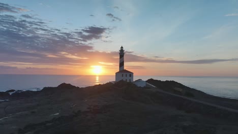 drone panning around famous lighthouse on the coast of spain with clouds lighting up the sky