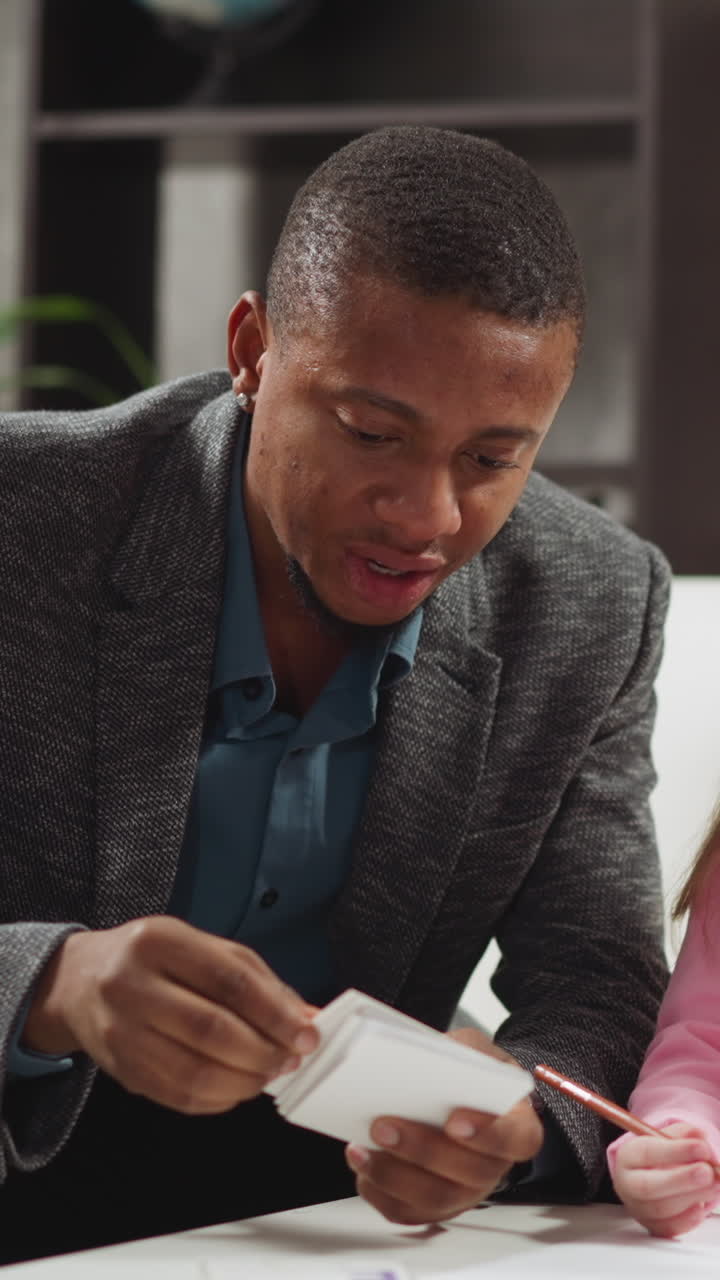 Black English teacher shows cards and tells letter names to little children studying foreign language during lesson with native speaker slow motion