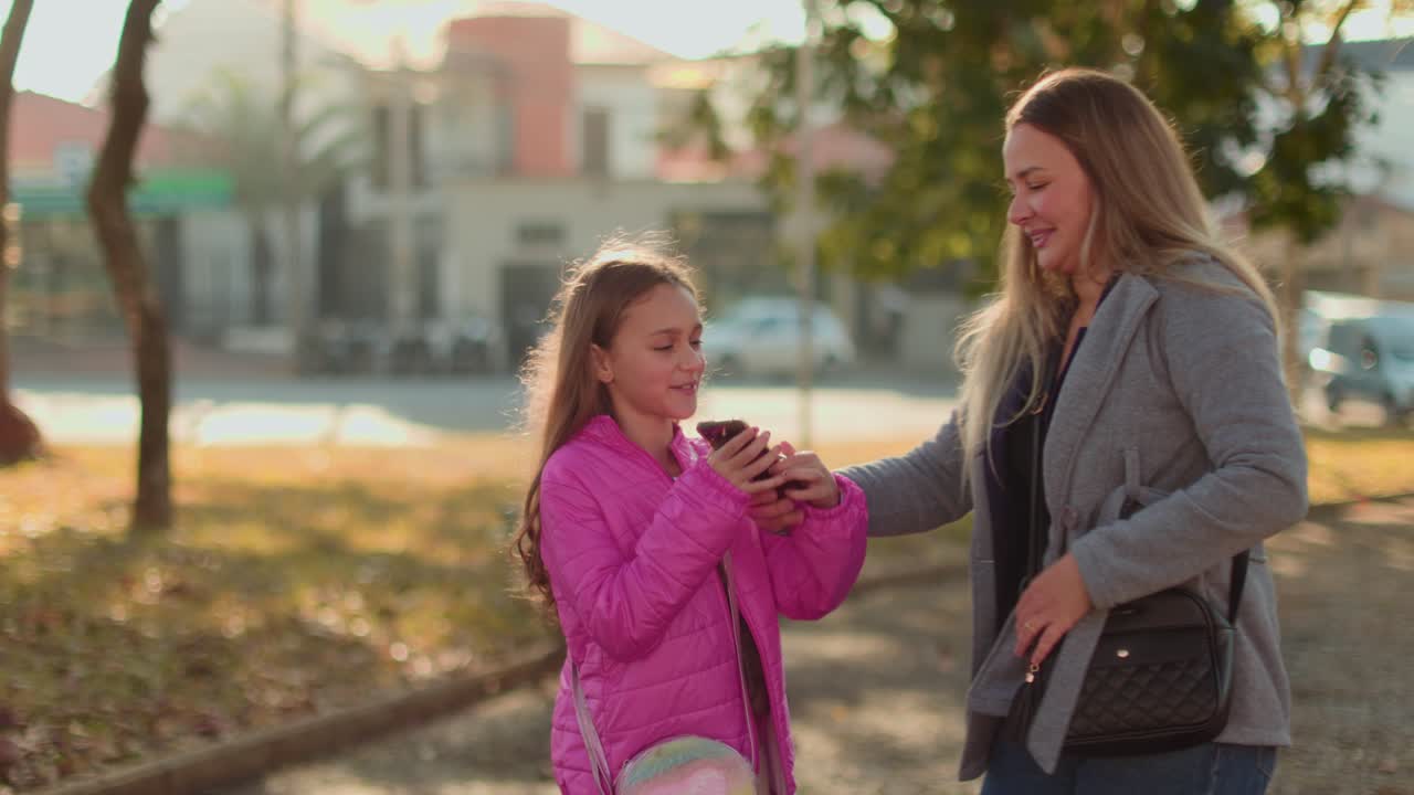 Madre e figlia che si godono il tempo insieme in un parco con uno smartphone.