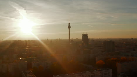 Autumn-Fall-Colored-Sunset-and-Nature-in-Big-City-with-TV-Tower-Skyscrape-in-center-of-Berlin,-Germany.-Aerial-Dolly-out-above-beautiful-Cityscape-in-Golden-light