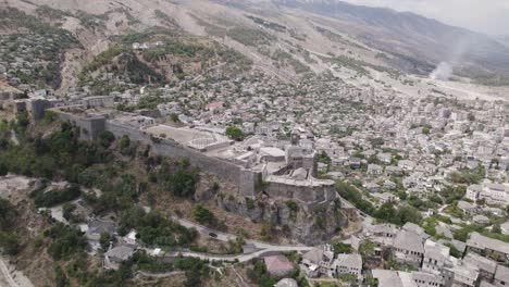 Drone-view-of-Gjirokastra-Castle-on-hilltop-overlooking-historic-UNESCO-World-Heritage-City-of-Gjirokastër,-Albania