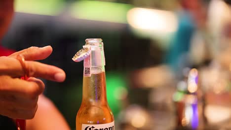 person opens bottle with a bottle opener