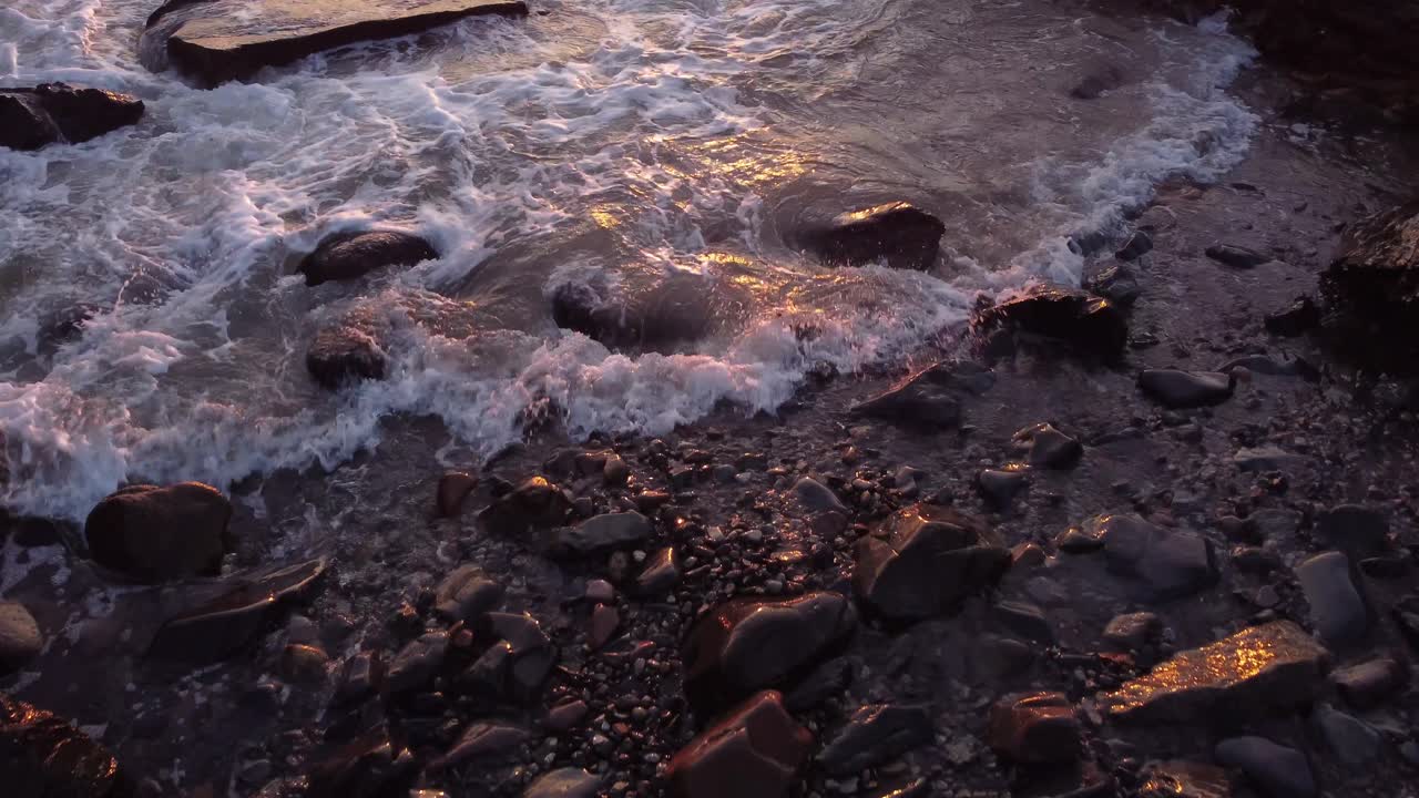 aereo di spiaggia rocciosa con le onde dell'oceano si schianta sulla costa durante il tramonto ore d'oro luce