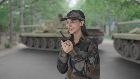 happy indian woman army officer talking on walkie talkie