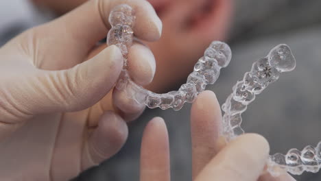 dentist examining two clear invisalign aligners side by side - slow-mo