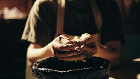 hands shaping clay in a pottery studio