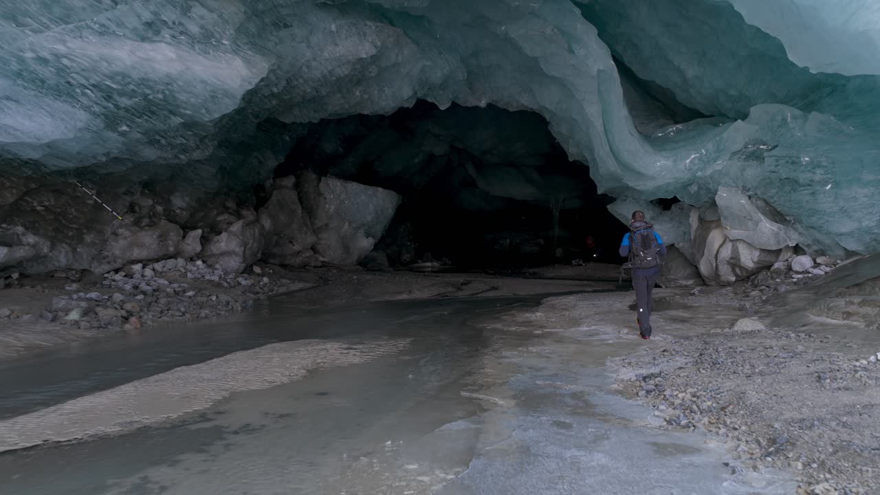 Person explores Morteratsch glacier ice cave, walking along meltwater stream, Stunning ice formations, ideal for adventure, nature documentaries, Switzerland