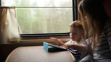 madre e hijo jugando al touchpad en el tren
