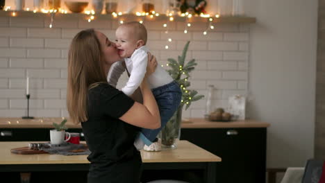 mother and her baby son having fun and playing at home. little kid 2 years old play with his mom arms at home near a big window