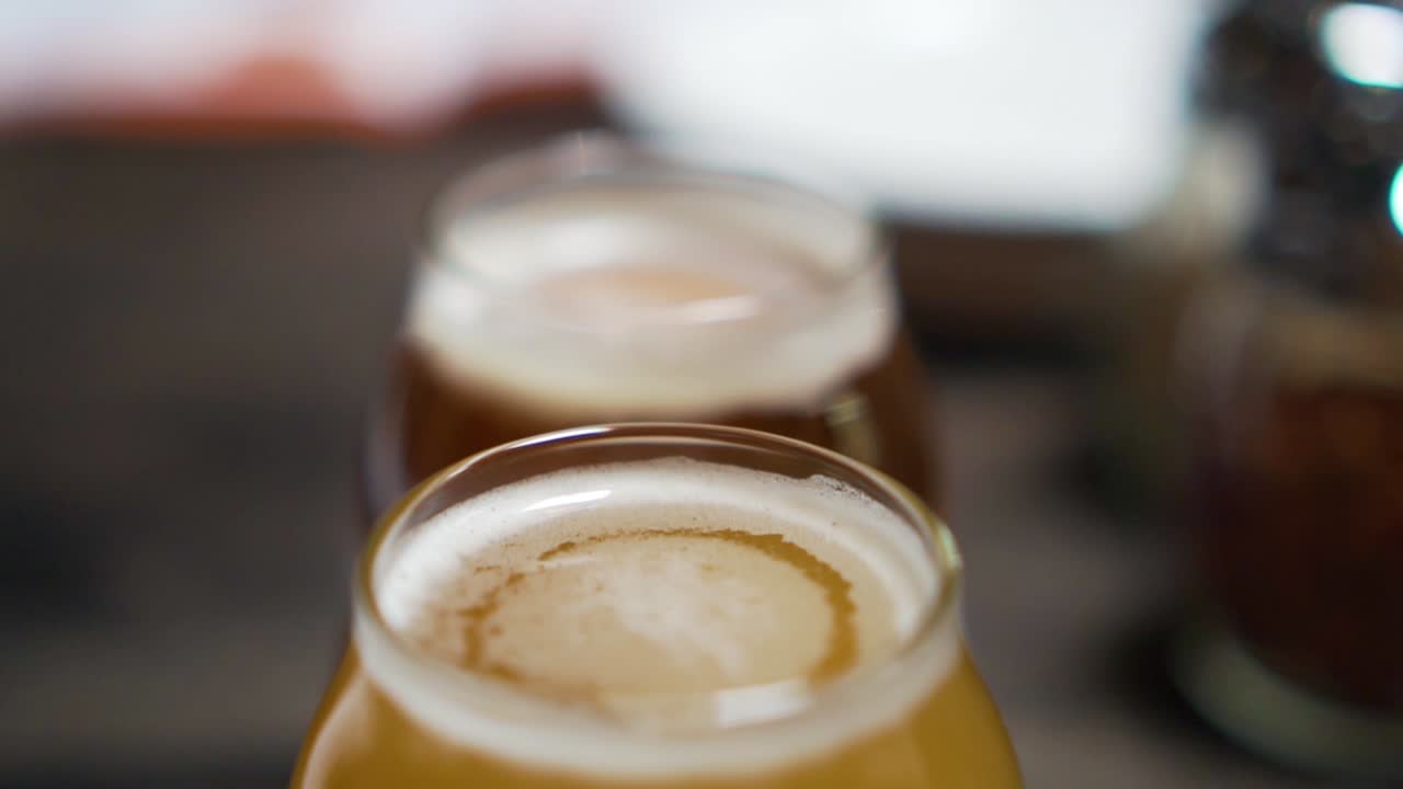 크래프트 맥주로 가득 찬 한 줄의 안경 위로 글라이딩 샷, 슬로우 모션