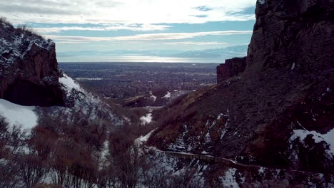 flying between rugged cliffs above a hiking trail towards the distant city