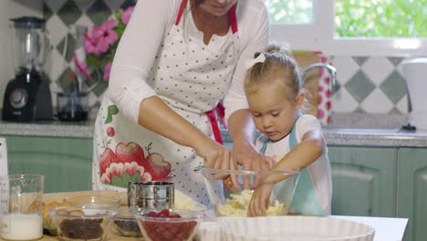 cute little girl helping her mother bake