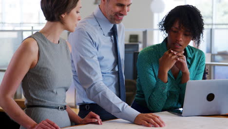 Three-architects-discuss-design-plans-in-an-office,-close-up