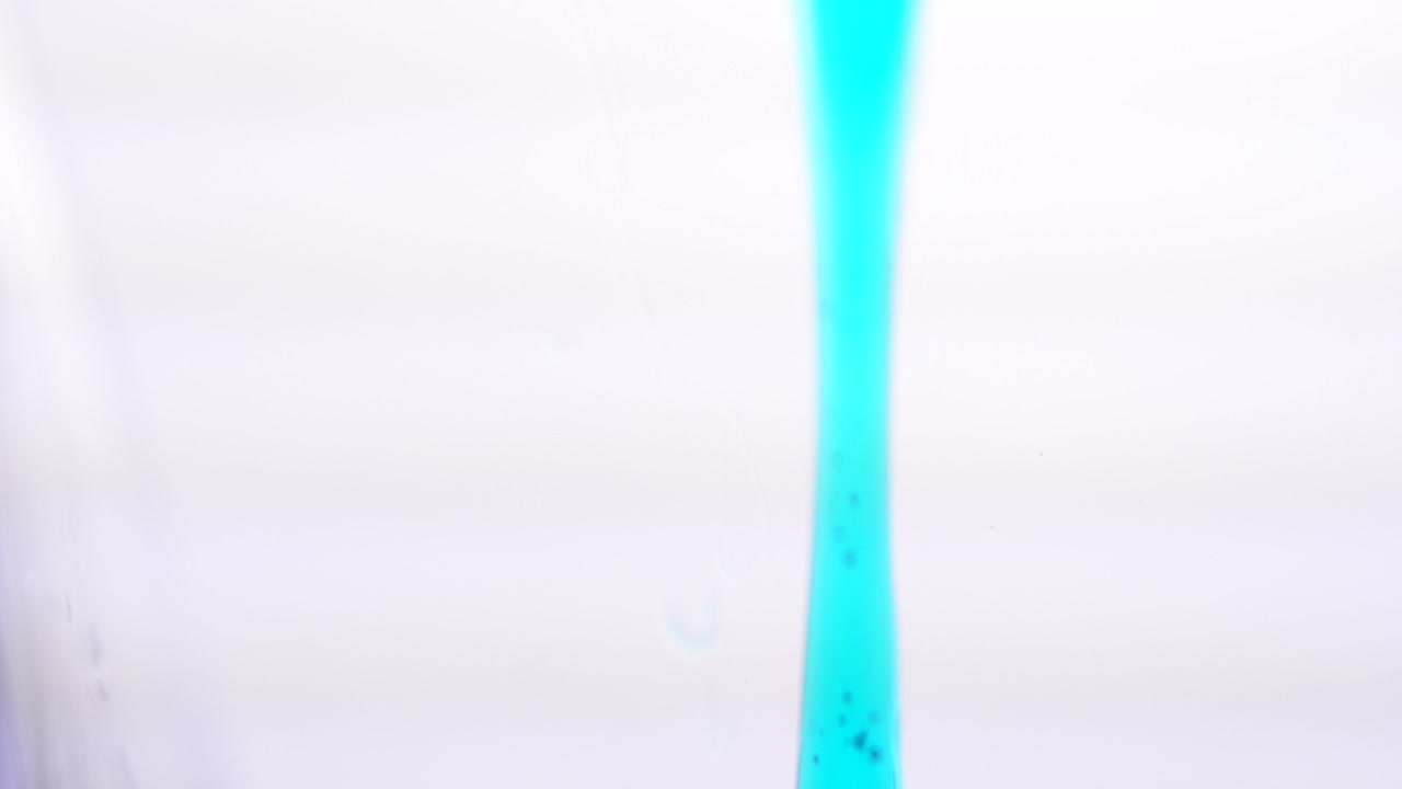 파란 액체가 유리잔에 어지고 있습니다.