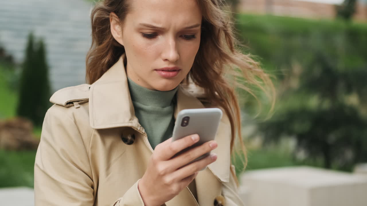 Caucasian female student using smartphone outdoors.
