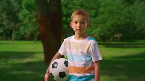 Junge-Mit-Fußball-Posiert-Mit-Der-Kamera-Auf-Der-Natur.-Ernsthafter-Kleiner-Sportler,-Nahaufnahme.